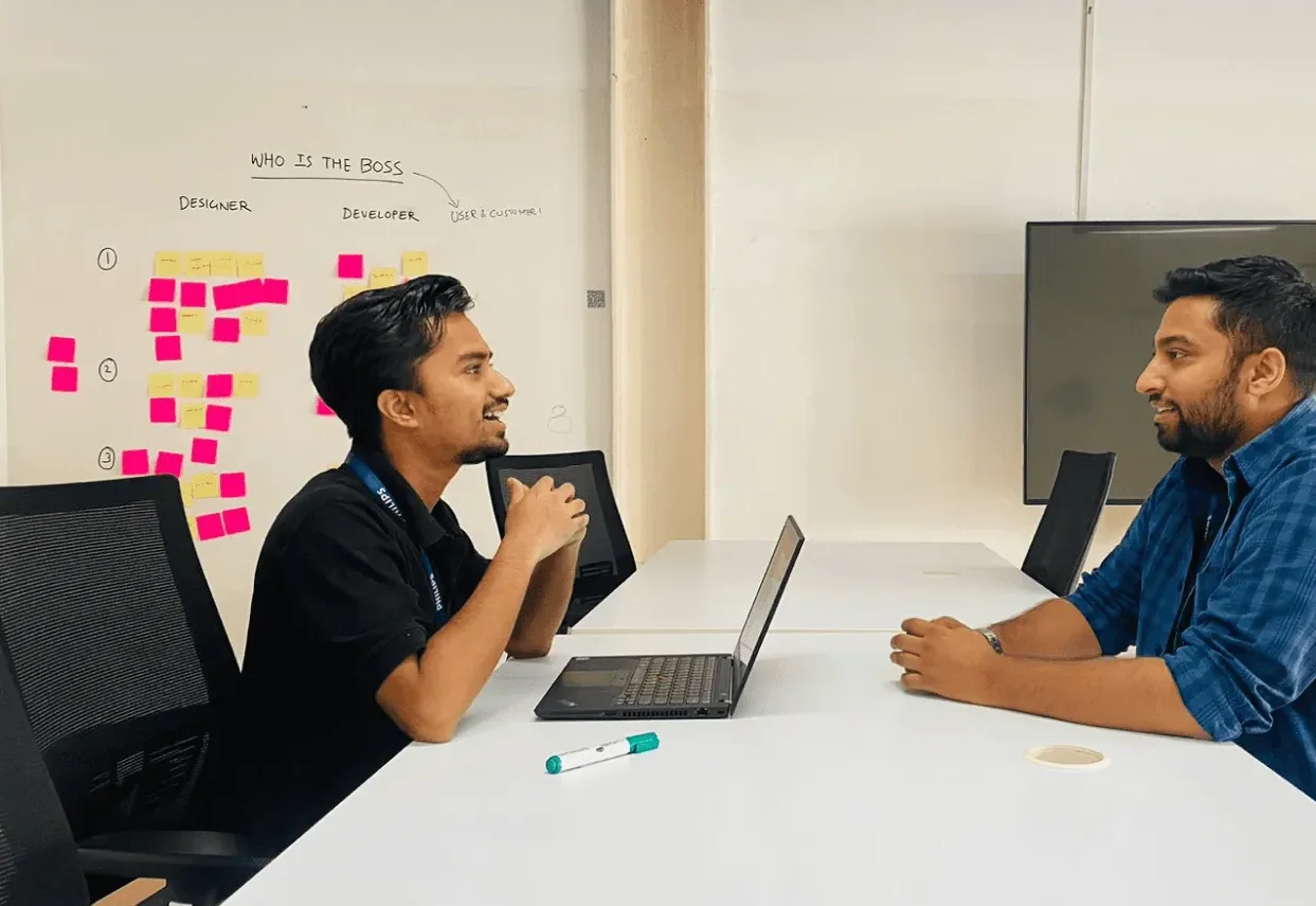 An interview session at Philips: two people talking across a table, a whiteboard of sticky notes behind them