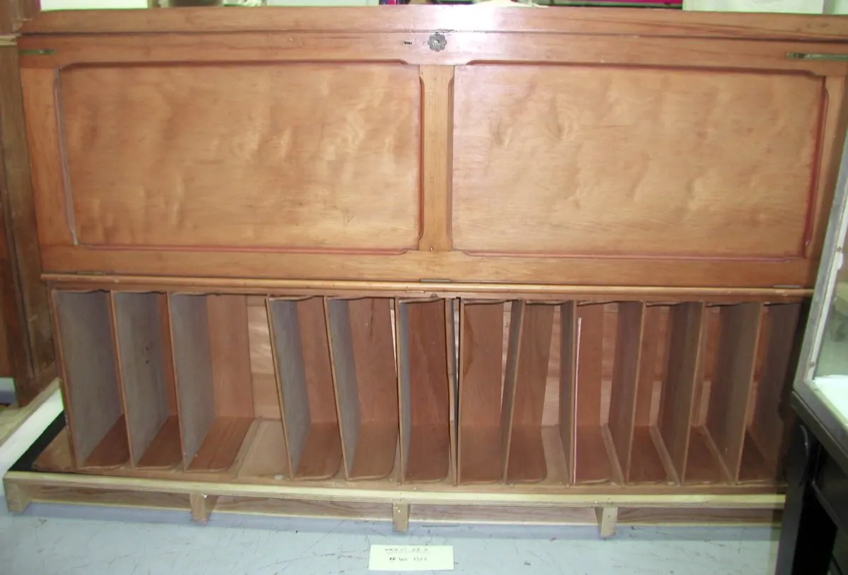 A tall wooden herbarium cabinet with rows of shallow drawers for storing pressed plant specimens.