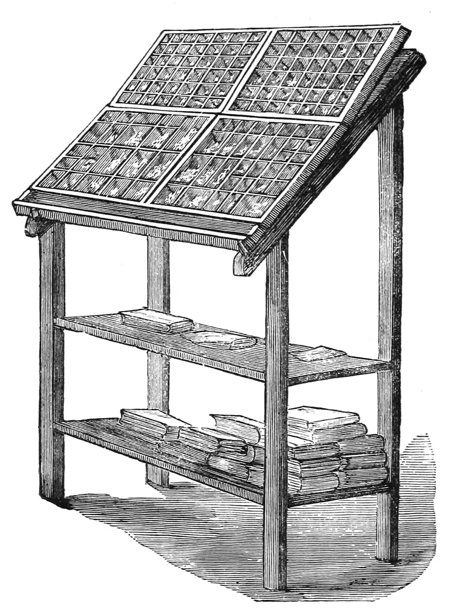 An old printer's type case, a shallow wooden tray split into many small compartments, each holding pieces of metal type.